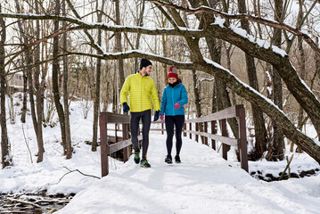 Cheerful couple walking on bridge in winter park