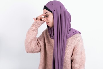 beautiful muslim woman wearing hijab and warm jumper over white background smelling something...