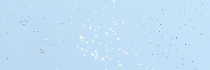Sparkling silver glitter on blue background banner texture. Abstract holiday blurred lights header. Wide screen wallpaper. Panoramic web banner with copy space for design
