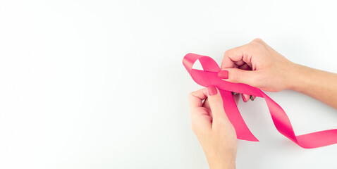 Cancer awareness. Health care symbol pink ribbon in woman hands on white background. Breast woman support concept. World cancer day.