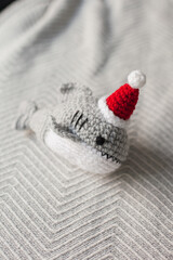 Fototapeta na wymiar Crocheted plush shark in Santa hats as Christmas gifts. Amigurumi toys handmade. Crochet hobby. Making DIY gifts for family and friends and kids. 