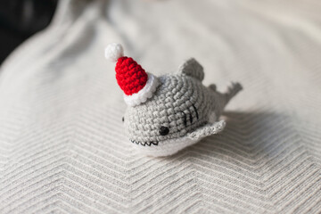 Crocheted plush shark in Santa hats as Christmas gifts.  Amigurumi toys handmade. Crochet hobby. Making DIY gifts for family and friends and kids. 
