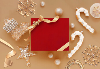 Fototapeta na wymiar Christmas background. Red gift box wrapped with golden ribbon on Christmas ornaments. Isolated on golden background and copy space. Top view. 