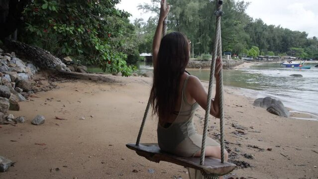 A lonely slender girl relaxes, walks along the beach. a swing on a wild beach