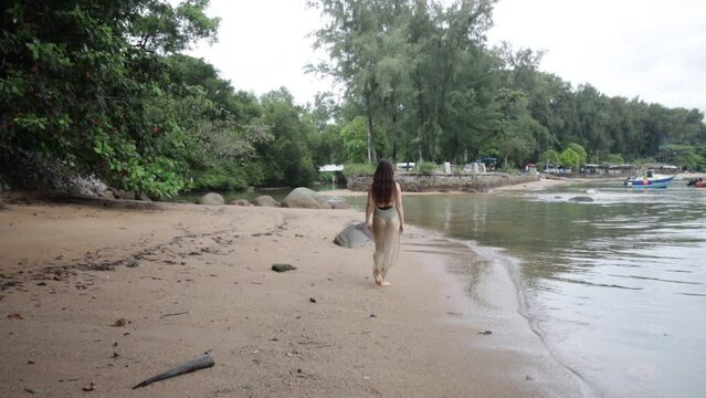 A lonely slender girl relaxes, walks along the beach. a swing on a wild beach