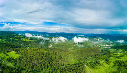 Valley of Balkan mountains with fog, sunny clouds and forests. Village Pamporovo. Panorama, top view