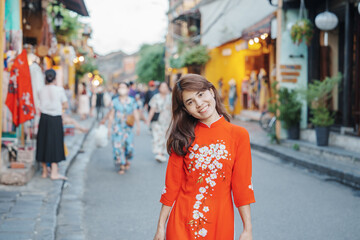 Fototapeta premium happy woman wearing Ao Dai Vietnamese dress, asian traveler sightseeing at Hoi An ancient town in central Vietnam. landmark and popular for tourist attractions. Vietnam and Southeast travel concept