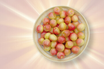 Fresh pink cherries in a plate on an abstract background. View from above. Close-up with copy space.