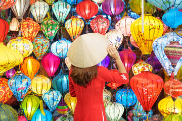 happy woman wearing Ao Dai Vietnamese dress with colorful lanterns, traveler sightseeing at Hoi An...