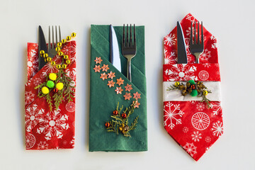 Red and green color, christmas pattern paper christmas napkins various folded with cutlery set on white surface