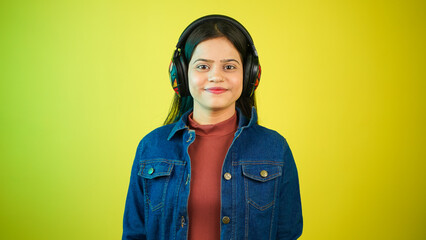 Young woman listening music with wireless headphones on her head, happy teenage girl enjoying music isolated over colour background