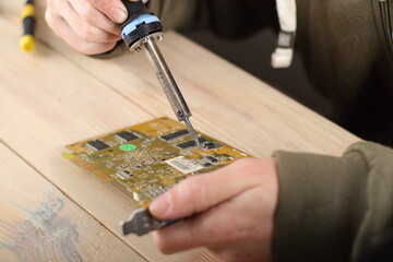 person soldering computer graphics card on table