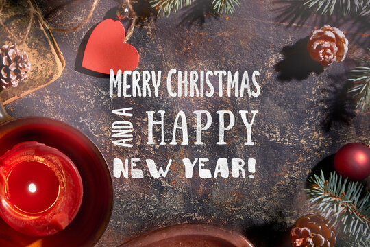 Merry Christmas and a Happy New Year Xmas dark vintage background. Red candle in ceramic jar. Xmas background with text, caption, Xmas greeting Merry Christmas and a Happy New Year. Natural fir twigs