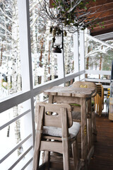 Terrace of the house overlooking the winter forest. There is a wooden chair and chairs on the terrace