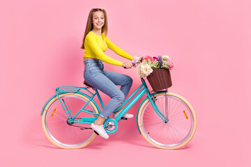 Full length photo of cute adorable schoolgirl wear yellow crop top driving bike isolated pink color...