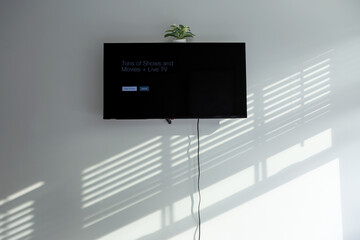 Television on a bedroom wall with cord hanging down
