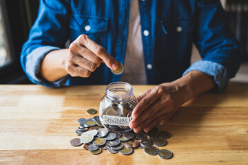 Woman puts a coin in a jar to save money for the future. after retirement and income, expenditure, savings and financial concepts