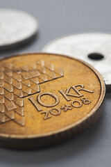 Norwegian coins lie on gray surface. 10 Norges kroner coin close up. National currency of Norway....