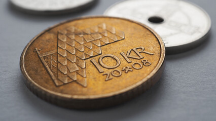 Norwegian money lies on gray surface. 10 Norges kroner coin closeup. National currency of Norway....