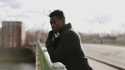 Thoughtful black African man thinking about life on top of a bridge