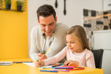 Fototapeta premium Little girl and her father enjoy drawing together at their home.