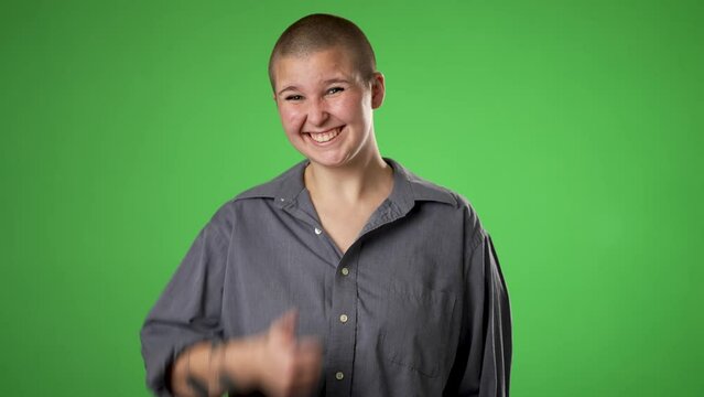 Smiling nod head yes gives thumbs up pretty gender fluid non binary young woman 20s 30s years old posing isolated on green screen background studio. Portrait sincere emotions lifestyle concept.