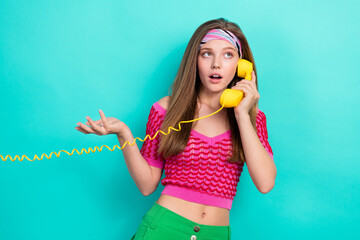 Portrait of interested adorable girl dressed pink top talking on landline phone look empty space isolated on teal color background