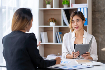 Two young Asian businessmen talk and discuss financial information. and the details planned by...