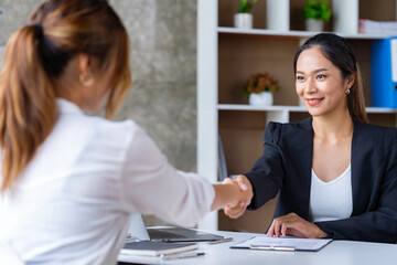 Fototapeta premium Attractive Asian business women shake hands after successful business deal, consensus business meeting.