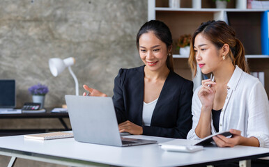 The collaborative process of young Asian business people team sitting and working with tablets together discussing, researching, brainstorming, and planning work in the office