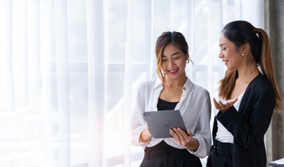 The collaborative process of young Asian business people team standing working with tablets...
