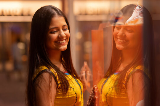 Cheerful woman with refection standing in front of mirror