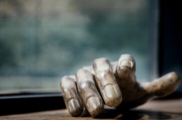 Closeup shot of wooden human's hand on a table near the window with its shadow on blurry background