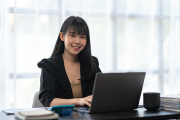 Business asian woman working on laptop computer managing her business in workplace, doing calculator planning document analyzing the financial report, business plan investment, finance analysis.