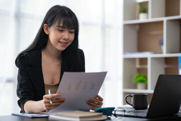 Portrait of Young Asian woman hand freelancer is working her job on computer tablet in modern office. Doing accounting analysis report real estate investment data, Financial and tax systems concept.