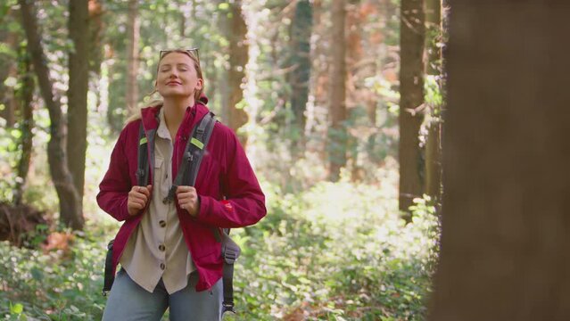 Woman taking deep breath and closing eyes enjoying peace as group of female friends on holiday hike through woods - shot in slow motion