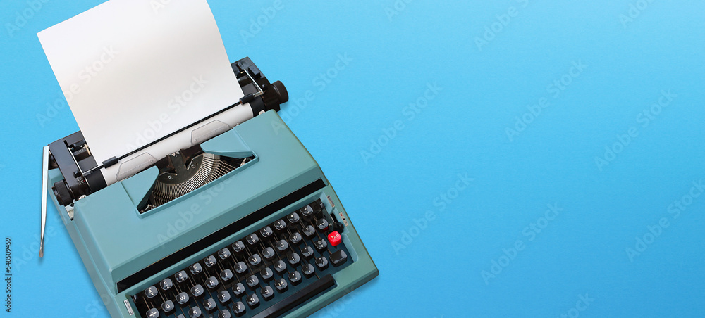 Fototapete retro typewriter with paper header with text space on blue background