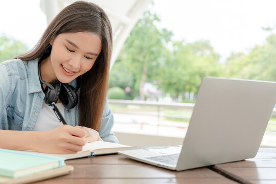 Beautiful Asian woman student excited check language test result on laptop. Smile girl happy study online. Portrait female on international Asia University. Education, school, book, college campus