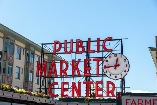 Red Public Market Sign With A Clock Before The Blue Skyline In Seattle