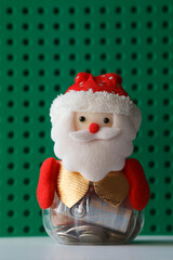 Santa Claus, Father Christmas moneybox, decorative fabric and plastic figure on green background