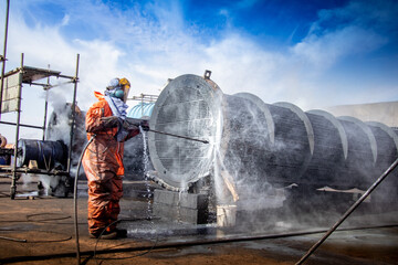 Tube bundle cleaning with high pressure water jetting under a cloudy blue sky. 