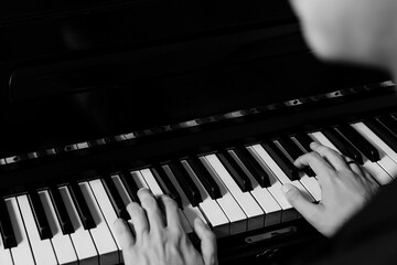 man playing the piano, black and white photo and keys close up