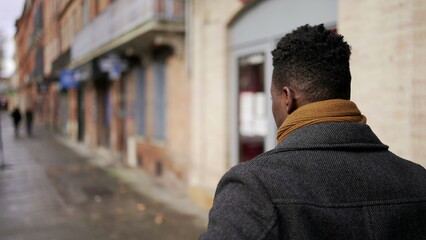 Young elegant black African man walking outside in city sidewalk