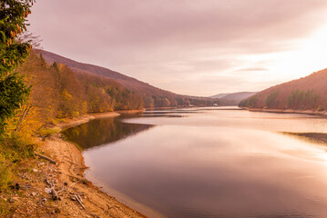 Beautiful lake in Romania, surrounded by trees with fall foliage. Reflection in water.