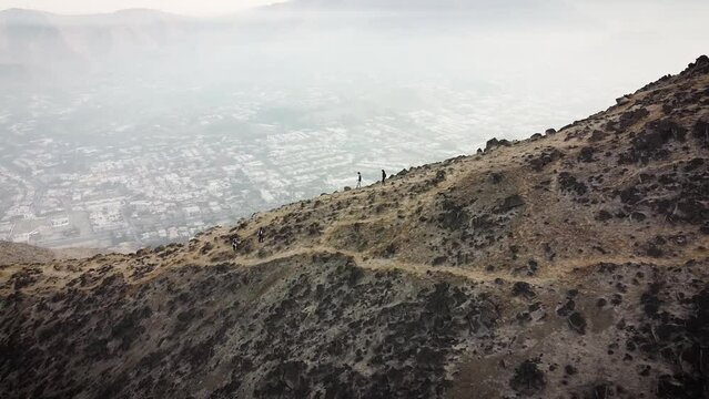 Circuling drone shot of hikers going down a crest on the mountains of the city of Lima Peru