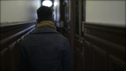 Naklejka na ściany i meble Young black man walking through corridor leaving house, person getting out