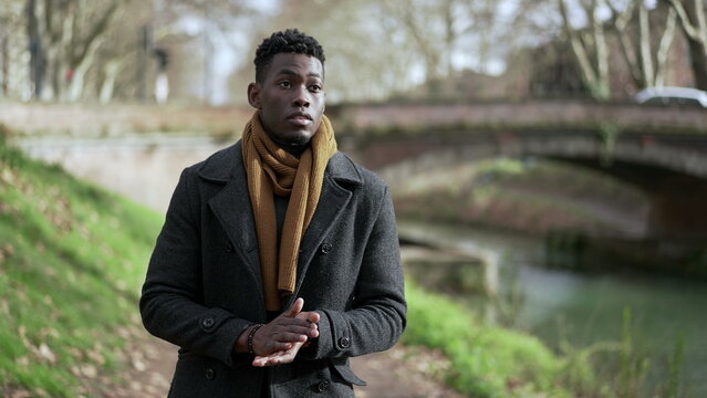 Young black man walking outside in nature during winter season