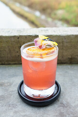 Selective focus of pink healthy herbal drink made from various Indonesian herbs with dried orange lemon and pansy flower (Viola tricolor) garnish put on raw wall table.