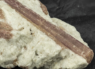 reddish tourmaline mineral sample on matrix on black background
