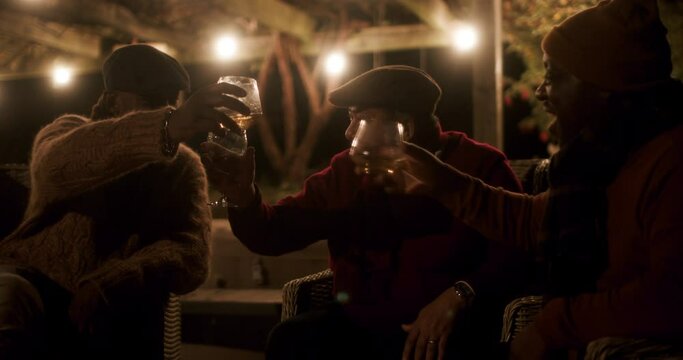 Men toasting with drinks on patio at night